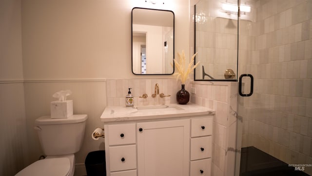 full bath featuring a stall shower, wainscoting, vanity, and toilet