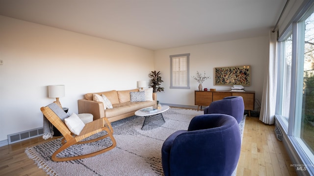 living room featuring light wood-style flooring, visible vents, and baseboards