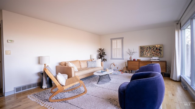 living room featuring wood finished floors, visible vents, and baseboards