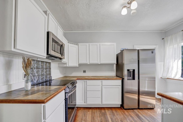 712 Yakima Ave, Filer, ID 83328 - kitchen with appliances with stainless steel finishes, a textured ceiling, light wood-style flooring, white cabinets, and crown molding
