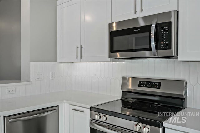 kitchen featuring backsplash, appliances with stainless steel finishes, white cabinetry, and light countertops