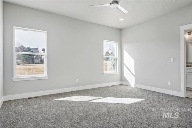 empty room with carpet flooring, visible vents, baseboards, and ceiling fan