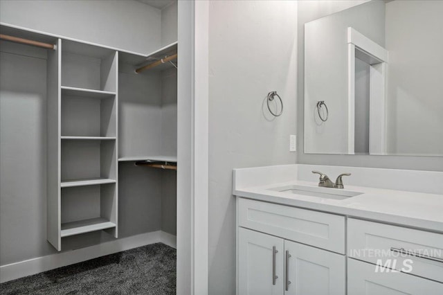 bathroom with a walk in closet, baseboards, and vanity
