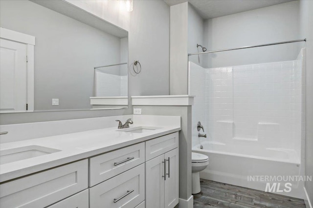 bathroom featuring double vanity, wood finished floors, toilet, and a sink