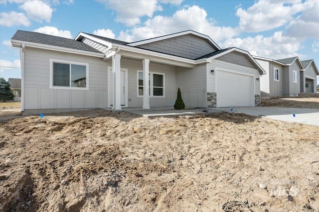 single story home featuring driveway, stone siding, a porch, board and batten siding, and a garage