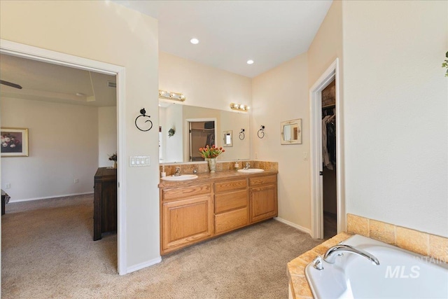 full bath with double vanity, a sink, a bath, and a spacious closet