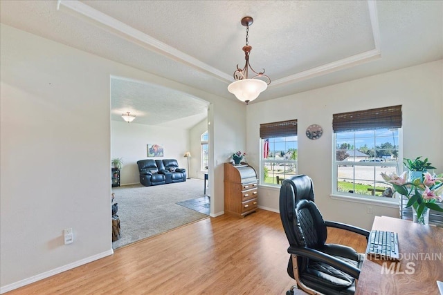 office area featuring baseboards, a textured ceiling, wood finished floors, and a tray ceiling