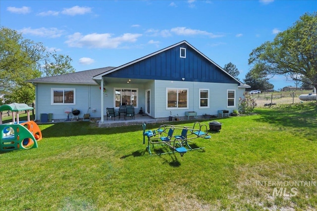rear view of property featuring board and batten siding, a patio, cooling unit, and a lawn