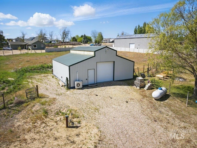 view of outdoor structure with an outbuilding, ac unit, fence, and driveway