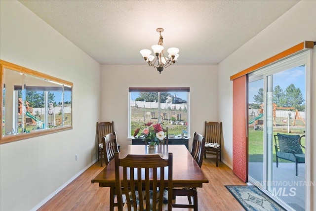 dining space featuring baseboards, plenty of natural light, light wood finished floors, and a notable chandelier