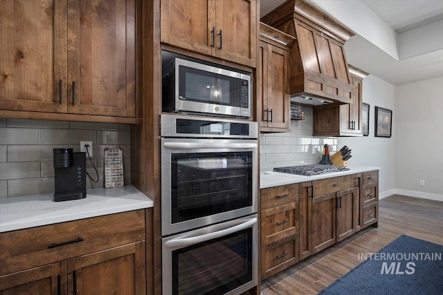 kitchen with dark wood-style floors, light countertops, backsplash, appliances with stainless steel finishes, and baseboards