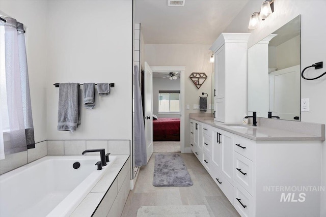 ensuite bathroom with visible vents, a ceiling fan, connected bathroom, a garden tub, and vanity