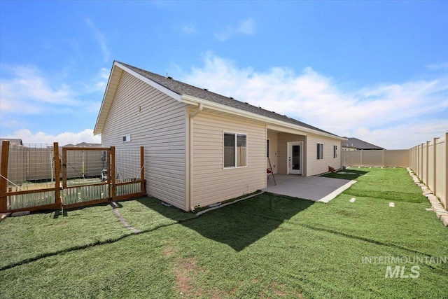 rear view of house featuring a fenced backyard, a patio, and a lawn