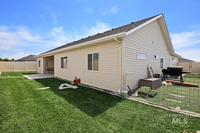 rear view of property with a yard, a patio, and fence