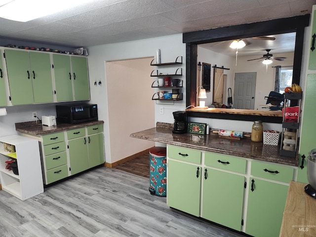 kitchen with light wood-type flooring, a barn door, ceiling fan, and green cabinets