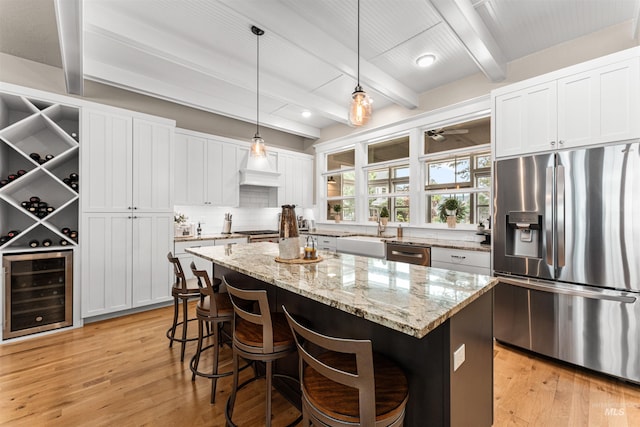 733 W Cowman St, Eagle, ID 83616 - kitchen featuring stainless steel appliances, beverage cooler, beam ceiling, backsplash, and a breakfast bar