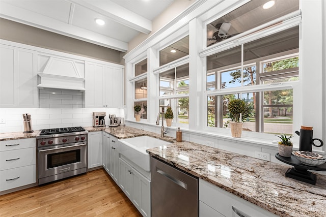 733 W Cowman St, Eagle, ID 83616 - kitchen featuring appliances with stainless steel finishes, decorative backsplash, light stone countertops, custom exhaust hood, and light wood finished floors