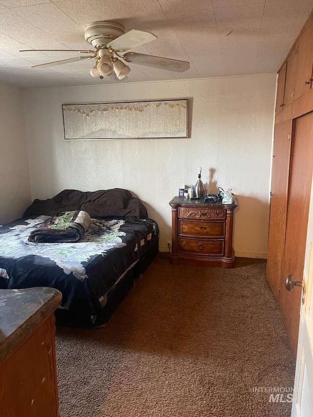 bedroom with a ceiling fan, a textured ceiling, carpet flooring, and a textured wall