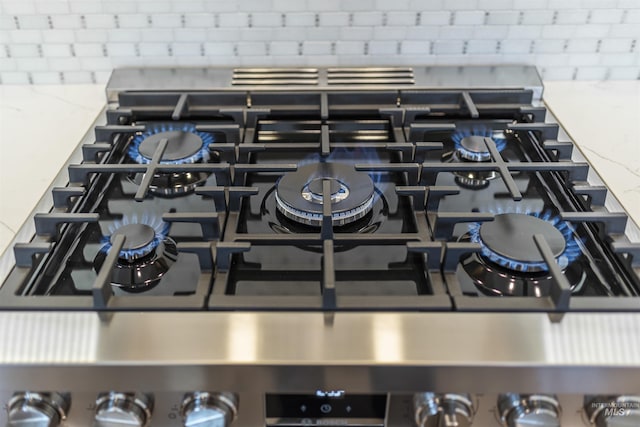 interior details with cooktop, light stone countertops, and stainless steel range with gas cooktop