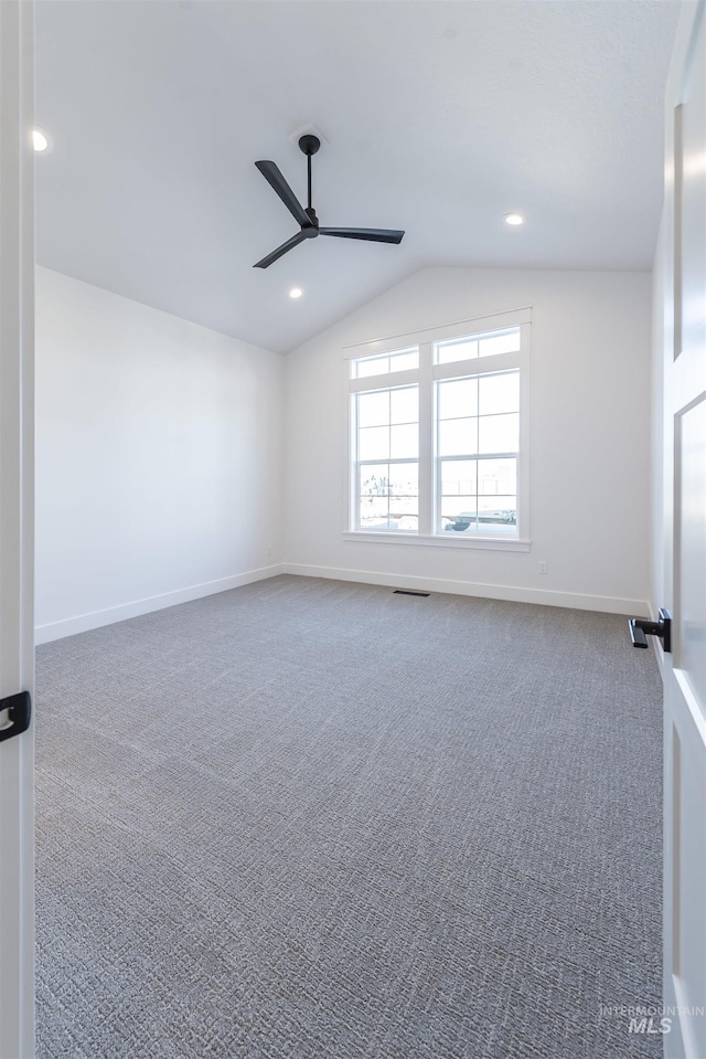 unfurnished room featuring carpet, visible vents, vaulted ceiling, ceiling fan, and baseboards