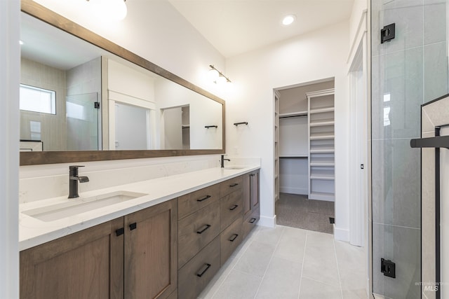 full bath featuring a stall shower, tile patterned flooring, a spacious closet, and a sink