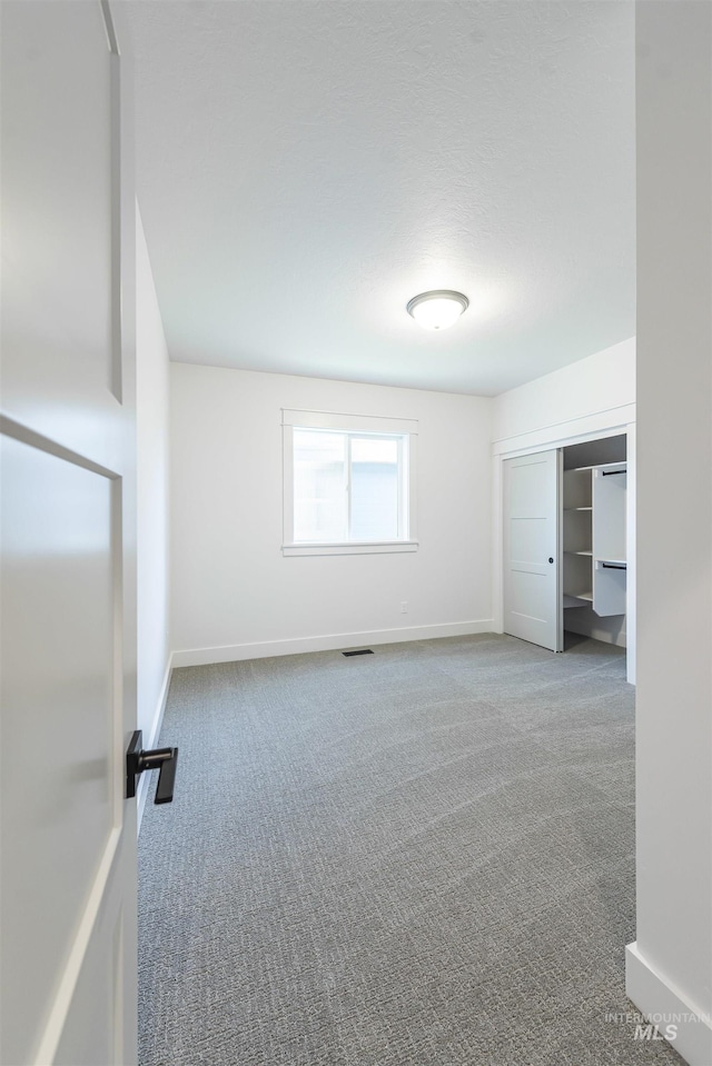 interior space with a closet, carpet flooring, visible vents, and baseboards