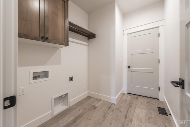 clothes washing area featuring hookup for an electric dryer, visible vents, baseboards, light wood-type flooring, and cabinet space