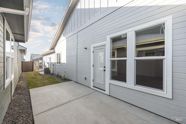 exterior space featuring board and batten siding, a patio area, fence, and central AC