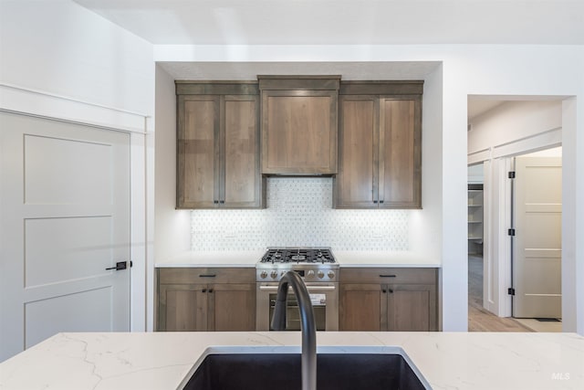 kitchen featuring light stone counters, extractor fan, high end stainless steel range oven, and decorative backsplash