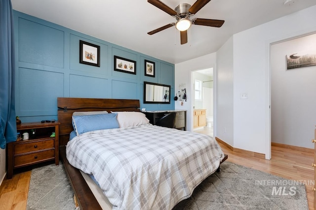 bedroom featuring ensuite bathroom, baseboards, ceiling fan, and light wood-style floors
