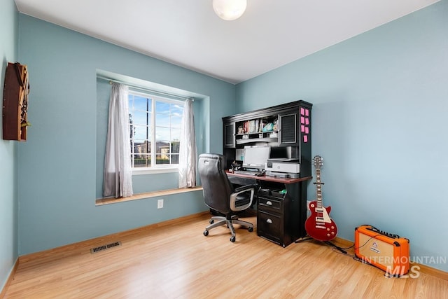 office space featuring wood finished floors, baseboards, and visible vents