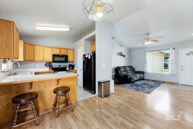 kitchen with a sink, open floor plan, black appliances, and vaulted ceiling