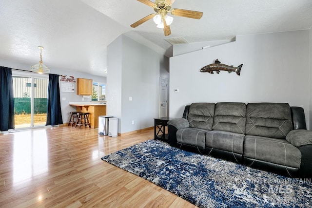 living room featuring light wood-style floors, visible vents, a ceiling fan, and lofted ceiling