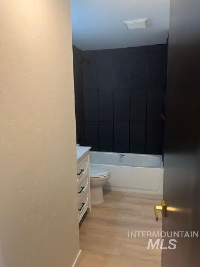 full bathroom featuring hardwood / wood-style floors, vanity, toilet, and tiled shower / bath