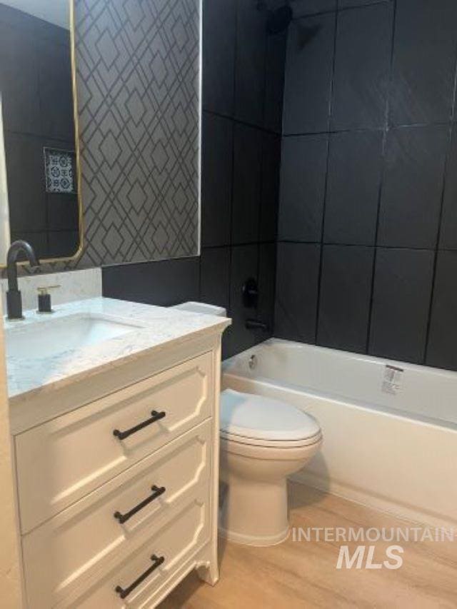 full bathroom with shower / bathing tub combination, hardwood / wood-style floors, vanity, and toilet