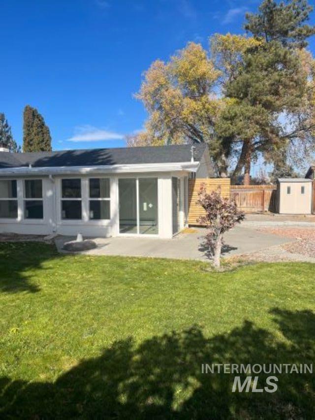 back of house with a storage unit, a yard, and a patio area