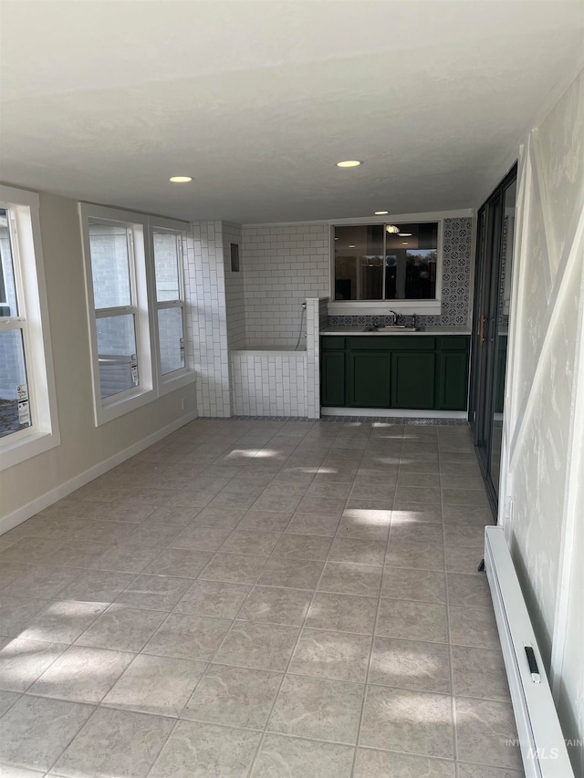 unfurnished living room with a baseboard radiator, sink, and light tile patterned floors