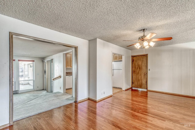 empty room with light wood-style floors, a textured ceiling, baseboards, and a ceiling fan