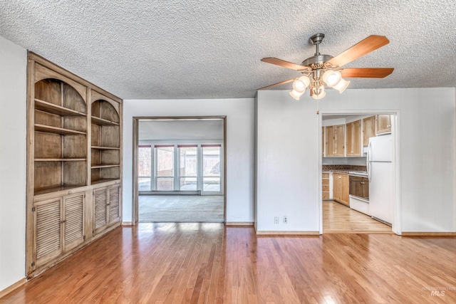 unfurnished living room featuring baseboards, ceiling fan, light wood-style flooring, and a textured ceiling