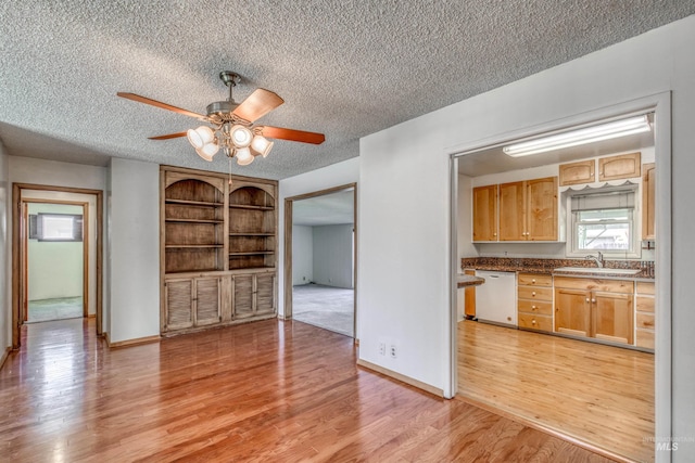 interior space with light wood-style flooring, ceiling fan, white dishwasher, a textured ceiling, and a sink