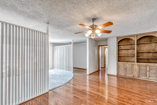 unfurnished living room with a ceiling fan, baseboards, a textured ceiling, and light wood finished floors