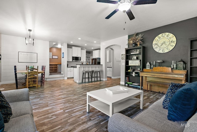 living area with ceiling fan, wood finished floors, recessed lighting, baseboards, and stairway