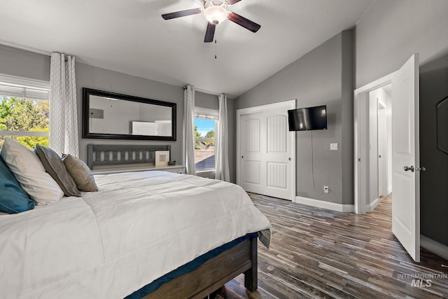 bedroom featuring vaulted ceiling, multiple windows, baseboards, wood finished floors, and a ceiling fan