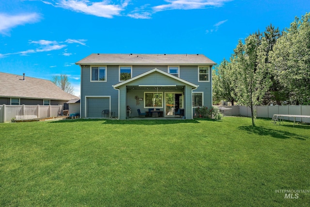 back of house with a garage, a trampoline, and a patio