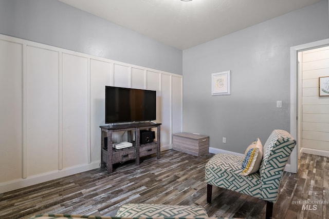 living room with a decorative wall and dark wood-type flooring