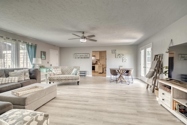 living area with a textured ceiling, a ceiling fan, a healthy amount of sunlight, and light wood-style floors