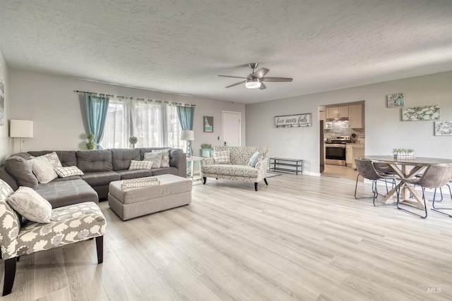 living room featuring light wood-style floors, ceiling fan, and a textured ceiling