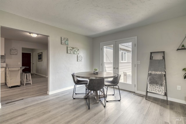 dining area with light wood finished floors, visible vents, french doors, and baseboards