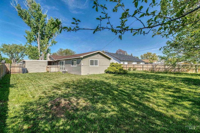 rear view of house featuring a yard and a fenced backyard