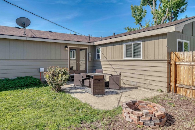 back of property featuring a lawn, french doors, fence, a patio, and a fire pit